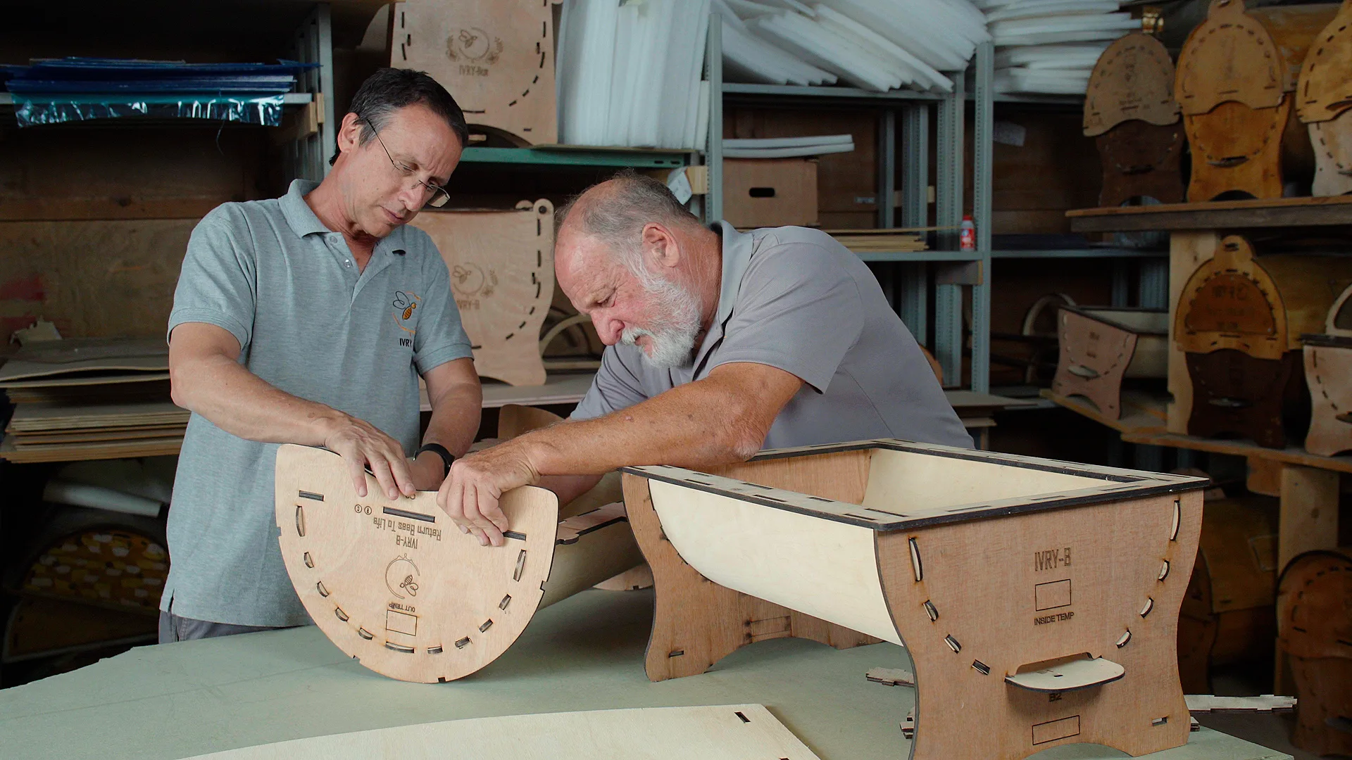 Two makers assembling a flat-pack Ivry-B hive in the workshop